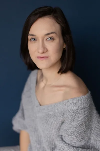 Magdalena Tarnawska-Stus - portret w białym topie i jeansach, neutralne tło
