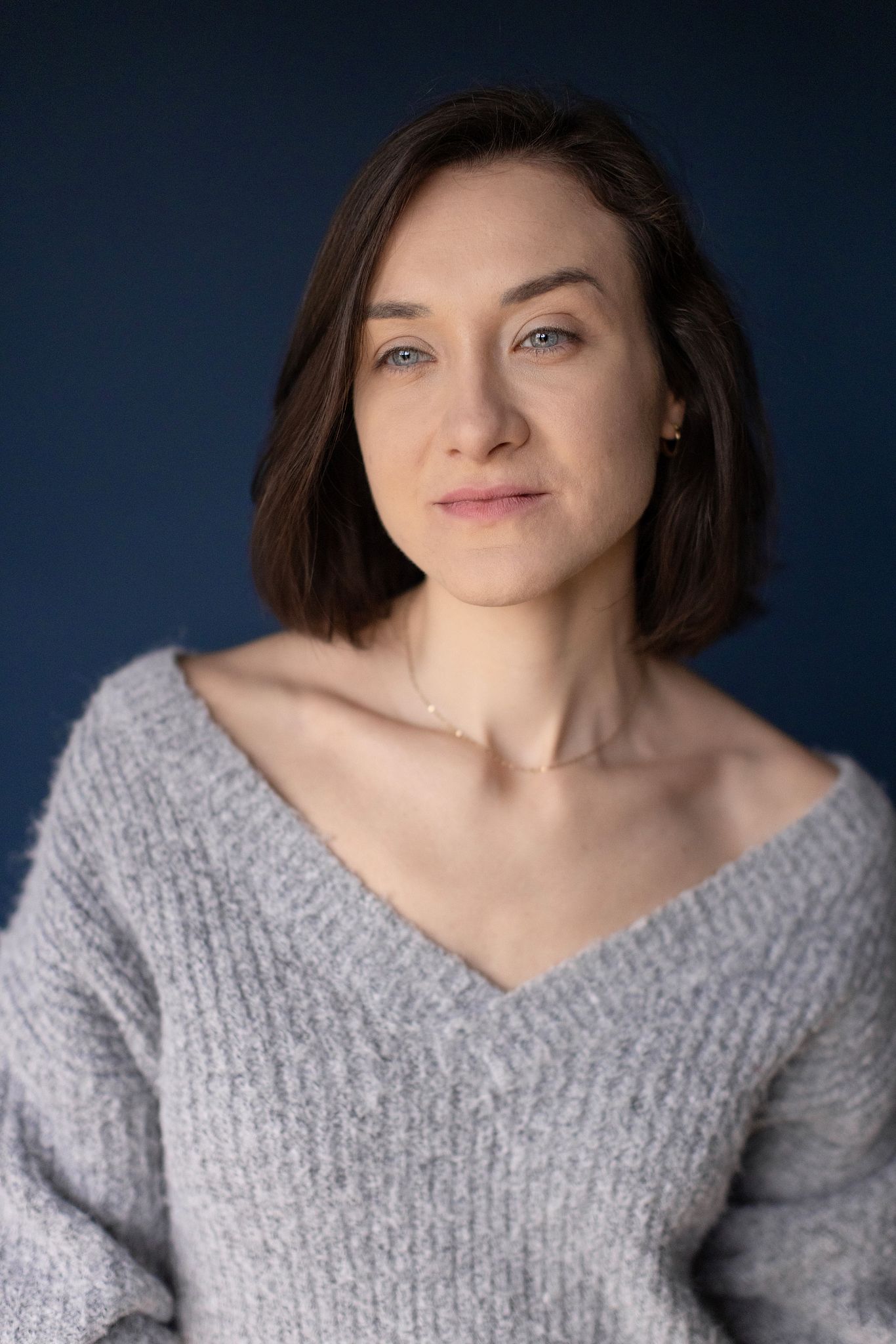 Magdalena Tarnawska-Stus - uśmiechnięty portret w jeansowej kurtce, neutralne tło