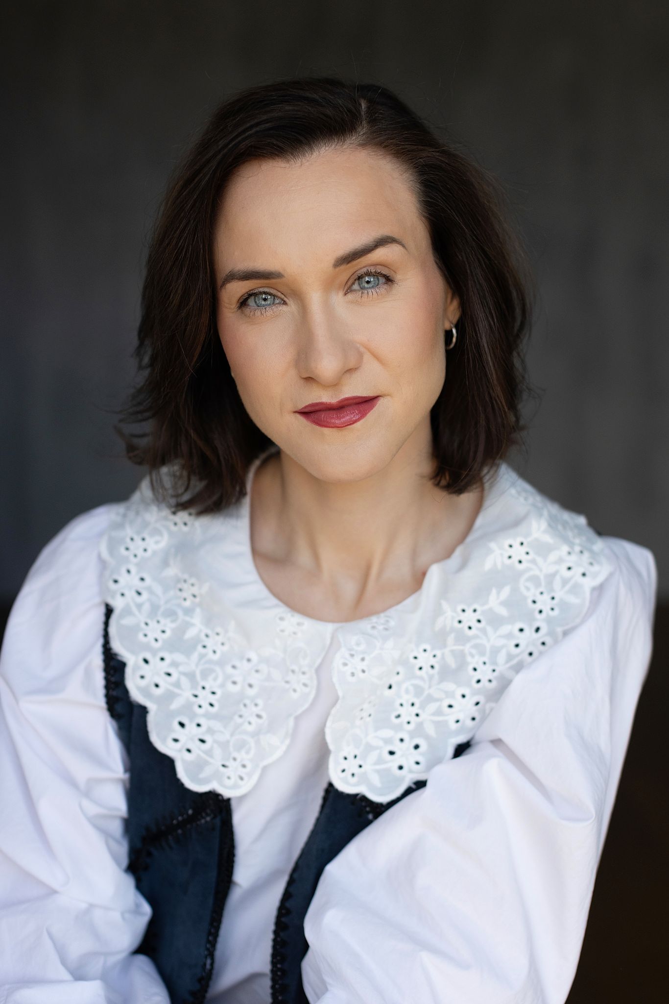 Magdalena Tarnawska-Stus - ujęcie siedzące w szarym komplecie, swobodna poza